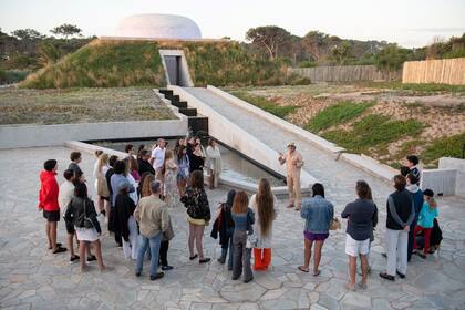 Robert Kofler habla con los turistas frente a la obra de arte "Ta Khut" creada por James Turrell, en Posada Ayana. Es el primer Skyspace freestanding (independiente) en América del Sur, un curioso domo hecho en mármol y cubierto de pasto a metros de la playa.