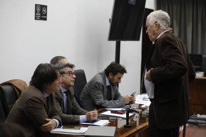 Roberto Ribas (parado), uno de los abogados de Nicolás Pachelo conversa con Gustavo Hechem, letrado que representa a Carlos Carrascosa y María Laura García Belsunce, esposo y hermana de la víctima, respectivamente