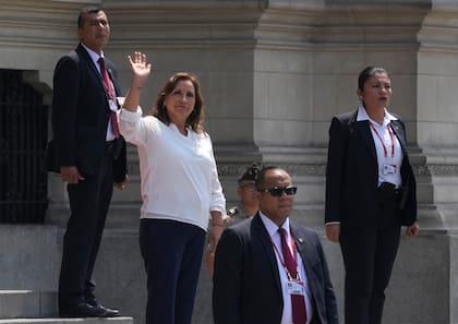 Rodeada de agentes de seguridad, la presidenta de Perú, Dina Boluarte, saluda a la prensa en el exterior del palacio presidencial, en Lima, Perú, el 10 de enero de 2023. (AP Foto/Martín Mejía)