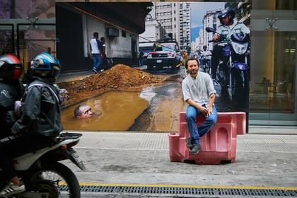 Rodrigo Abd en la vereda de Arthaus, delante de una gigantografía de una de sus fotos, tomada en Venezuela en 2013