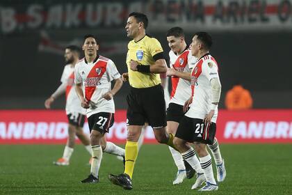 Rodrigo Aliendo, Julián Álvarez y Esequiel Barco rodean al árbitro chileno Roberto Tobar, que anuló por mano el gol de Matías Suárez que conducía la serie con Vélez a una definición por penales.