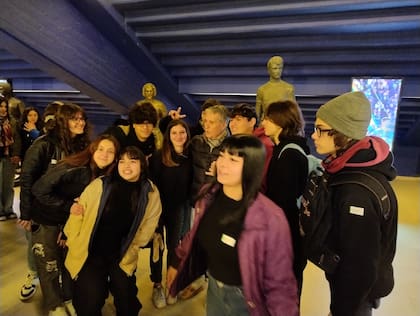 Rojitas, rodeado de jóvenes estudiantes en la Bombonera; detrás suyo, su propia estatua