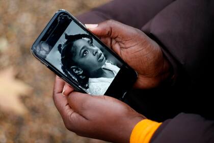 Rosamund Adoo-Kissi-Debrah sostiene su teléfono móvil y muestra una fotografía de su hija Ella Adoo-Kissi-Debrah, quien murió en febrero de 2013 de un severo ataque de asma