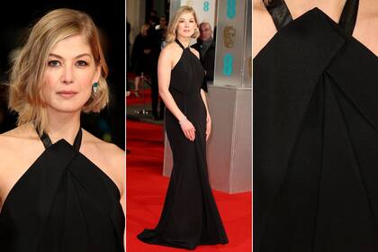 Rosamund Pike, con un vestido negro de cuello halter con lazo de raso atado al cuello, un diseño sobrio y elegante de Roland Mouret