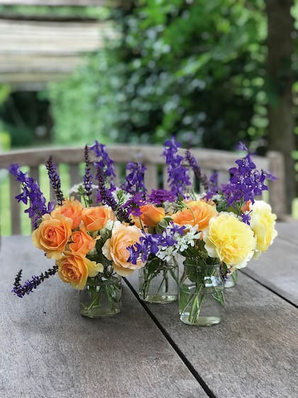 Rosas ‘Anne Harkness’ y ‘Molineux’ combinadas con varitas de espuelas de caballero, salvias y orlayas en unos vasos reciclados de yogur