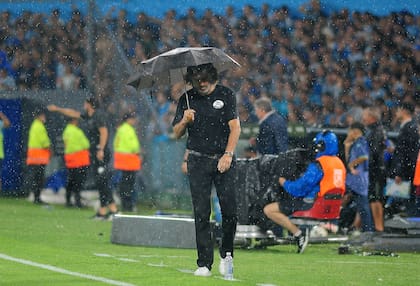 Ruben Darío Insua bajo el aguacero, con un paraguas que no alcanza a cubrirlo del agobio por la situación de San Lorenzo.