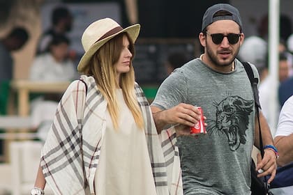 Sábado 4 de julio, 13 horas. Isabel y Martín Tassara llegan al campo de polo de La Santísima Trinidad. Ella vistió un oxford de jean, con top escotado en la espalda, un chal a cuadros de Burberry y un panamá