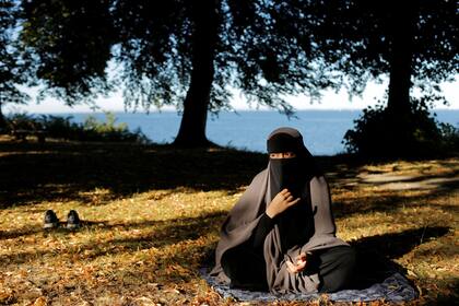 Sabina, de 21 años, usuaria del niqab y miembro fundadora del grupo Kvinder I Dialog (Mujeres en diálogo), hace una pausa después de rezar en un parque junto al mar en Copenhague.