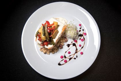 Salmón sobre risotto de longaniza, vegetales crujientes y salsa de yogur y lima .