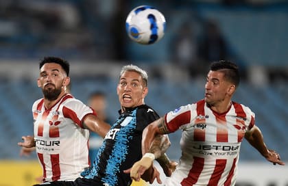 Santiago Brunelli y Horacio Salaberry tratan de marcar a Enzo Copetti