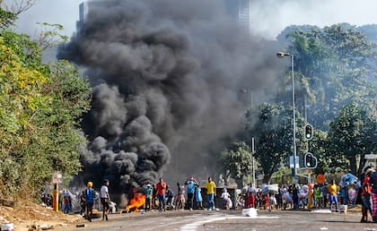 Saqueadores junto a una barricada en llamas en Durban