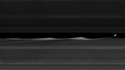 Daphnis, una luna de 8 kilómetros de diámetro encajada en el anillo de Saturno levanta ondas mientras orbita dentro de la brecha de Keeler.