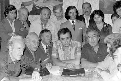 Saúl Ubaldini y Fernando Donaires (secretario adjunto), en una reunión de la CGT tras el anuncio de la recuperación de Malvinas; detrás Carlos Menem, gobernador de La Rioja, y la dirigente del PJ Malva Herrera; los rodean los miembros del consejo directivo y de las 62 organizaciones