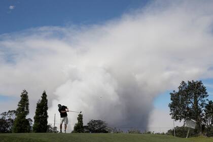 Un hombre juega al golf mientra la lava del volcán no deja de avanzar