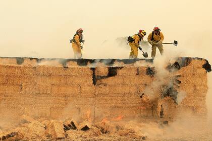 Los bomberos de Arcadia y Santa Rosa intentan apagar una pila de fardos de heno