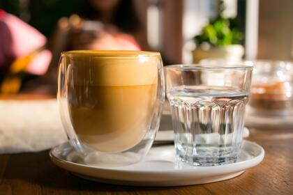 Una taza de café con leche se sienta en un platillo con tazas de café.
