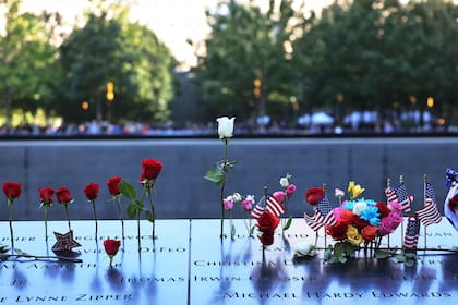Flores y banderas de los Estados Unidos en los nombres de las víctimas durante la ceremonia anual de conmemoración del 11 de septiembre