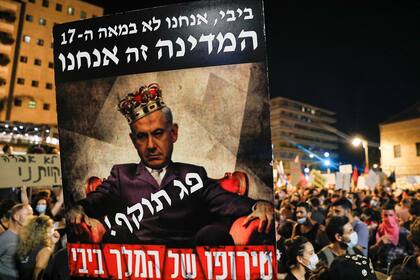 Se levanta un póster durante las protestas que muestra al primer ministro israelí Benjamin Netanyahu con una corona y una palabra sobre su pecho que lee en hebreo "expiró" sobre otra frase que dice "la locura del rey Bibi"
