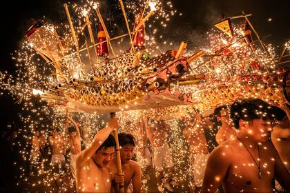 Elección de la gente, Categoría Gente, la imagen es de Léo Kwok, varias personas en Meizhou, China, realiza una danza del dragón de fuego, bañada por chispas de hierro fundido que arrojan fuegos artificiales para celebrar el Festival de los Faroles