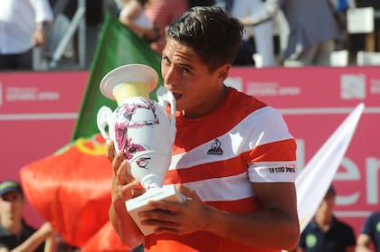Sebastián Báez, "mordiendo" a lo Rafa Nadal, el trofeo de campeón del ATP de Estoril. 