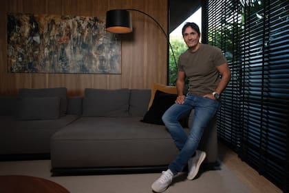 Sebastián Estevanez
posa en un rincón de
su living, decorado en
colores oscuros y con
detalles de madera.
Detrás de él, un
cuadro pintado por su
madre, la artista Moni
Cuomo.
