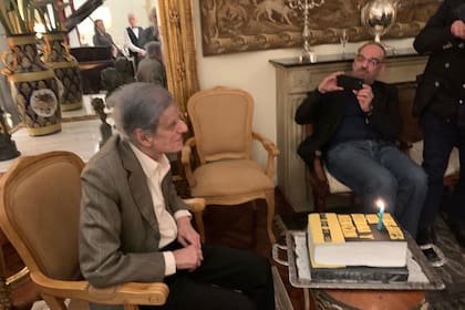 Sebreli soplando las velitas de la torta libro de su cumpleaños 92