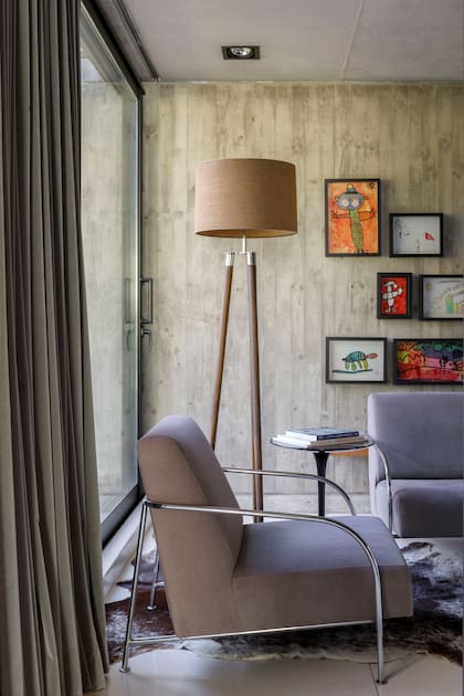 Sector de lectura con sillones de estructura cromada tapizados en pana, mesa de arrime ‘Saarinen’ con tapa de mármol negro ‘Marquina’ y lámpara de pie (Fábrica de Luz).