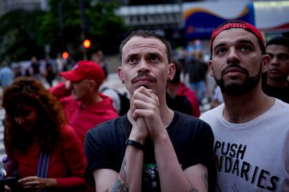 Seguidores del expresidente brasileño Luiz Ignacio Lula da Silva, quien vuelve a postularse para presidente, ven en una pantalla los resultados parciales luego del cierre de las urnas para las elecciones generales en Sao Paulo, Brasil, el domingo 2 de octubre de 2022. (Foto AP/Matias Delacroix )