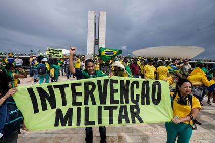Seguidores del expresidente Jair Bolsonaro sostienen un cartel que dice "Intervención Civil y Militar!"