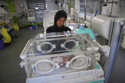 Seham Fawzy Khodeir observa a su hijo, Hisham, que nació prematuramente y sólo ha vivido unos días, dentro de una incubadora en la unidad de terapia intensiva para recién nacidos del hospital Nasser, el jueves 19 de junio de 2025, en Jan Yunis, en el sur de la Franja de Gaza. (AP Foto/Mariam Dagga)