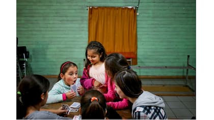 Selenna, izquierda, juega cartas durante un descanso con otras chicas durante una clase de baile en su centro comunitario en Santiago de Chile