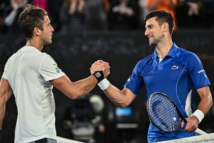 Serbia's Novak Djokovic (R) speaks with Argentina's Tomas Etcheverry after victory during their men's singles match on day six of the Australian Open tennis tournament in Melbourne on January 19, 2024. (Photo by Lillian SUWANRUMPHA / AFP) / -- IMAGE RESTRICTED TO EDITORIAL USE - STRICTLY NO COMMERCIAL USE --�