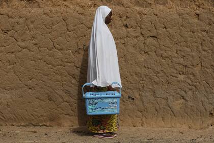 Shamsiya Muktar, una estudiante de la escuela secundaria para niñas del gobierno, que escapó de su escuela, posa para un retrato con su caja escolar en su casa, el día después de que casi 300 alumnas fueran secuestradas por bandidos en Jangebe, una aldea en el estado de Zamfara, al noroeste de Nigeria el 27 de febrero de 2021