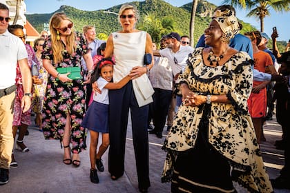 Siempre cercana, Máxima se deja abrazar por una niña, ante la mirada encantada de Amalia, que complementó su vestido con unos aros dorados de su mamá.
