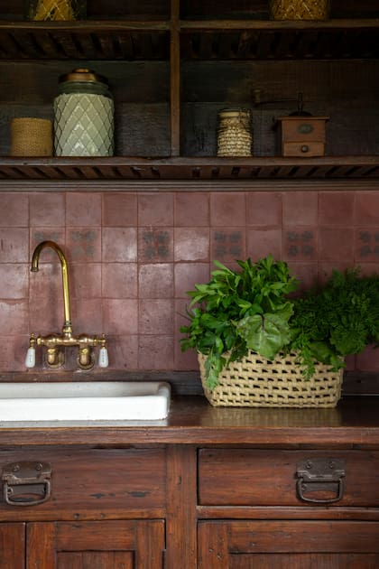 Siguiendo la estética de cocina de campo, bacha enlozada, grifería de bronce y muebles bajomesada con herrajes antiguos. La alzada de calcáreos suma calidez.