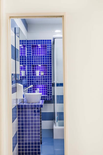 Siguiendo la línea del living, en el baño todo es azul, celeste y blanco en materiales vitrificados. Las mesadas y estantes se hicieron en material, igual que el sillón del living.