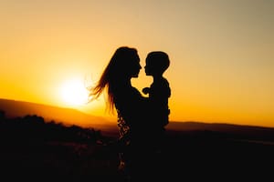 Silhouettes of mother and child in her arms on the background of sunset sky