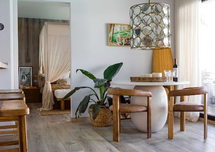 Sillas 'Arco' tapizadas, mesa en madera laqueada con pie oval y lámpara colgante traída de Indonesia (todo de Wood Market). Obra 'América', de Maia Croizet (Diderot.art).