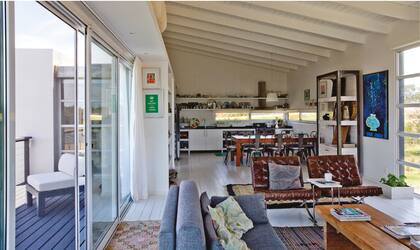 Sillas Barcelona en cuero avejentado y kilim turco antiguo (todo de Marabierto). Junto a la estantería de teca con lustre blanco y metal hecha en Indonesia, diseñada como exhibidor para Marabierto, óleo del artista polaco Darek Pala.