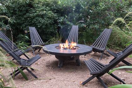 Sillas pintadas de negro alrededor del fogón. En los alrededores se dejaron crecer pastos palmera, que se resiembran naturalmente