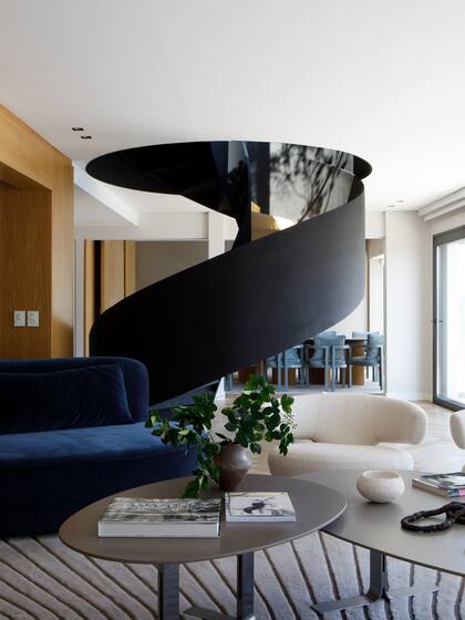 Sillón a medida en pana azul y dúo de mesitas con patas de acero y tapa laqueada (Estudio Cali Herrera). Alfombra ‘Ralph’ en bajo relieve (Jt. Pfeiffer)