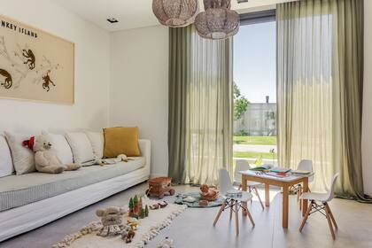 Sillón (Arq. Maura Ambrosetto) con funda off-white y colchoneta con funda verde a rayas, a tono con las cortinas (Solset). Cuadro bordado (Estudio Polonia) y lámparas colgantes de La Feliz.