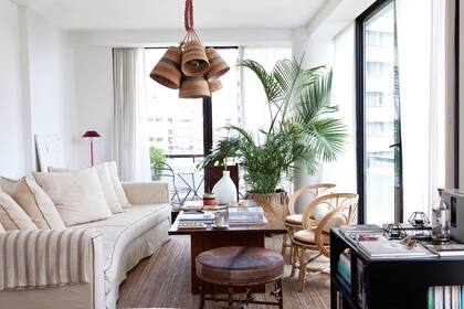 Sillón curvo (Laura O). Sillas ‘Mar del Plata’ (Hermanas Marcovecchio). Banqueta con asiento de cuero. Mesa de lapacho heredada, alfombra de yute (Ikea). Canasto (Sentido). Palmera (Vivero Mario).