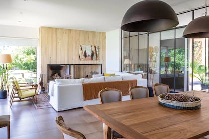 Sillones de un cuerpo (Mercado Libre). Lámpara de pie (La Pantalla). Alfombra (Mihran). En el comedor, mesa y canasta (Valsen); y sillas de madera lavada, retapizadas en lino color visón.