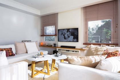 Sillón esquinero y diván, Mmsas bajas con patas en cruz y tapa en laca blanca. Mueble de TV de laca blanca con estante en lapacho (todo hecho a medida por Bienestar Deco). Almohadones (Kasbah).