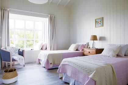 Sillón individual y cortinas (Esteve Quintana). Mesa de luz (Lorenzo Cañete para Constructora VZ). Almohadones, acolchados y mantas al pie de las camas (Blanquita Home).