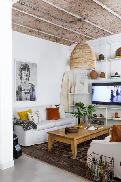 Sillones con almohadones (Maru Bardó, la marca deco de la dueña de casa), alfombra (Sir Xristian), lámpara de techo (Compañía Nativa). Sobre la mesa de centro, cuenco de cerámica (Antes Pella) con tira de cuentas negras (Lorettina) y bolas de madera (Vienede).