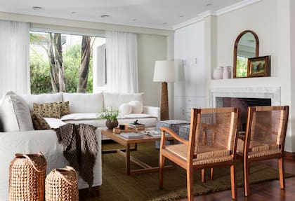 Sillones individuales y mesa de centro (Soleil Deco). Alfombra (Awanay). Manta (Lote Propio). En la chimenea, piezas de cerámica en bizcocho (Antes Pella). Pisos de madera (Zárate Parquet). Cortinas (Fedan).