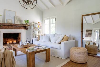 Sillones (La Impronta). Manta (Lote Propio). Mesa de centro (Maifren). Canasta de fibras naturales (Flox). Lámpara de techo (Omniluz). Espejo (El Camino Studio). Puf de yute (Hometh). Alfombra (Rugit).