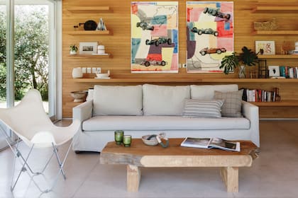 Sillones (Tapicería Do Braz) con almohadones de Lote Propio, silla ‘BKF’ (Morph) y mesa baja de ciprés (Carpintería Sebastián Fernández Lando) con velas (Bohemia Velas), cuenco de papel maché (Mamá Elefanta) y obra de arte textil (Entrelazados).